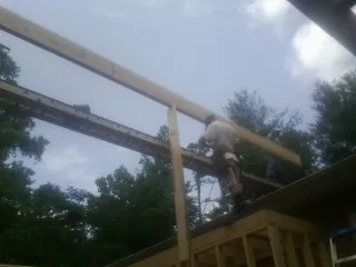 Carpenter setting a ridge beam over a new addition frame — Ice Dam Removal by Roofing Brothers in Pennock