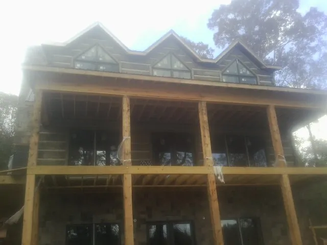 Dormers and porch framing on a large log home under construction — Roof Coating work by our crew in Pennock