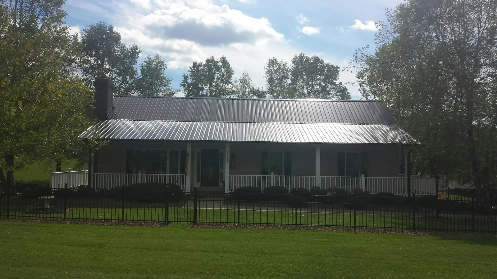 Gray metal roof on a brick ranch with a full width front porch — Gutter Guard Installation work by our crew in Pennock