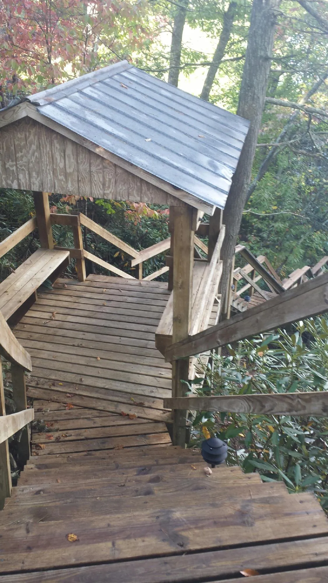 Metal roofed shelter over wooden steps on a wooded walkway — Skylight Repair & Installation work by our crew in Pennock